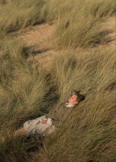 a man laying in tall grass on top of a field