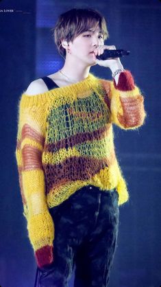 a person on stage with a microphone in their hand and wearing a sweater that is knitted to look like stripes