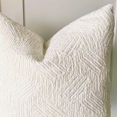 a white pillow sitting on top of a wooden table next to a wall mounted clock