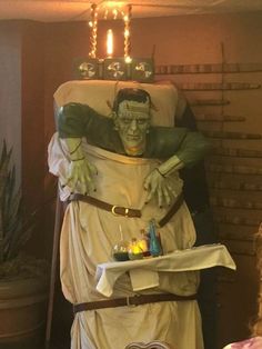 a statue of a man dressed as an alien holding a tray with candles on it