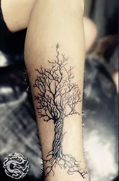 a woman's leg with a tree tattoo on the bottom half of her arm