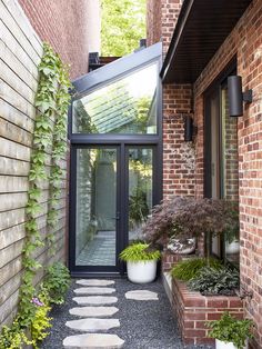 a brick building with a glass door and walkway leading to the outside area, surrounded by greenery