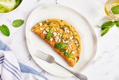 a piece of pizza on a plate with a fork and glass of water next to it