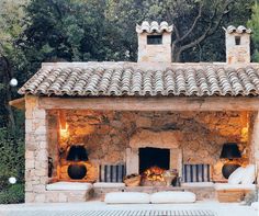 an outdoor fireplace in the middle of a stone building with two lamps on each side