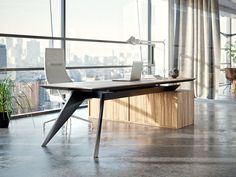 an office desk with a laptop on it in front of a large window overlooking the city