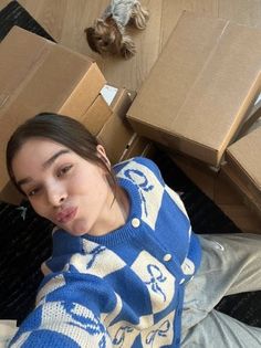 a young woman laying on the floor next to boxes with her head tilted down and looking at the camera