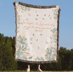 a person standing in front of a large blanket with the words john 3 16 on it