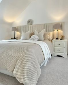 a white bed sitting in a bedroom next to two lamps on either side of it