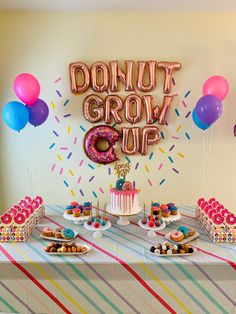 a donut grow up birthday party with balloons and desserts on a table in front of a sign that says donut grow up