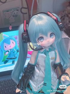 a close up of a doll wearing headphones near a computer keyboard and monitor screen