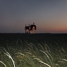 an image of a house that is in the middle of some tall grass at night