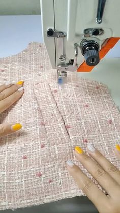 two hands with yellow fingernails are using a sewing machine to sew on the fabric