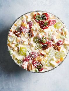 a bowl filled with fruit and nuts on top of a blue table next to a spoon