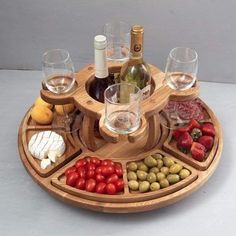 a wooden tray with wine glasses, cheese and vegetables on it that is shaped like a platter