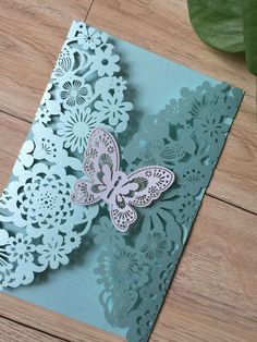 a card with a butterfly on it sitting on a wooden table next to a plant