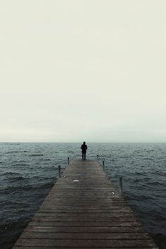 a person standing on a pier looking out at the ocean