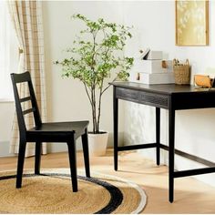 a desk and chair in a room with a potted plant on the floor next to it