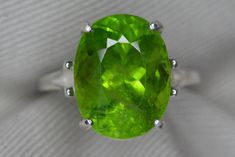 Please note that this peridot has been set in such a way that the stone will be in contact with the finger of the person wearing this ring.  Perfect for anyone wanting to wear peridot for its metaphysical properties. This fabulous ring contains a genuine earth mined peridot gemstone. This stone contains moderate inclusions as you would expect to see in any natural peridot of this size. The green color in this gem is absolutely stunning. The size 6 1/2 ring is made of solid sterling silver and can be sized up or down by as much as 2 sizes for $25.   This item is brand new and was appraised by a gemologist at Federal Gemological Laboratory Of Canada. The appraisal will be included and describes the item as follows:  Shape And Cut: Oval Weight: 10.95 ct Species: Natural Peridot Color: Green T Green Faceted Gemstones For Anniversary, Faceted Green Gemstones For Formal Occasions, Green Large Gemstones For Anniversary, Large Green Gemstones For Anniversary, Formal Green Faceted Gemstones, Formal Faceted Green Gemstones, Formal Large Green Gemstone, Anniversary Large Green Gemstones, Peridot Color