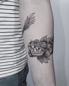 a man with a tattoo on his arm has a flower and an alligator's teeth