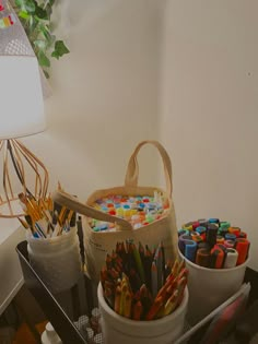 there is a basket full of crayons and pencils next to a lamp