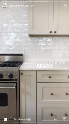 a stove top oven sitting inside of a kitchen next to white cupboards and drawers