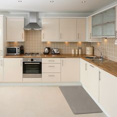 a kitchen with white cabinets and light wood counter tops