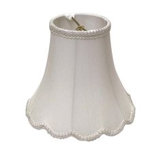 a white lamp shade with scalloped edges and a gold twig on the bottom