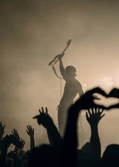 a person on stage with their arms in the air and hands raised up as they perform