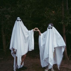 two people dressed in white capes holding hands