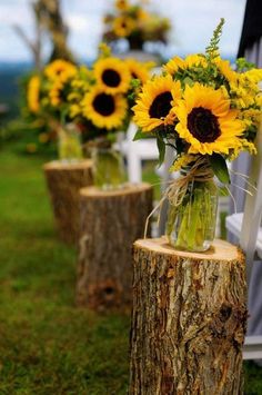 the sunflowers are in vases on the tree stump for ceremony decorating