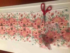 some pink flowers and red scissors on top of a white tablecloth with floral designs