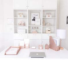 a white desk topped with lots of shelves filled with books and office supplies next to a laptop computer