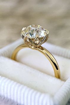 a yellow gold ring with an oval cut diamond on top in a white velvet box