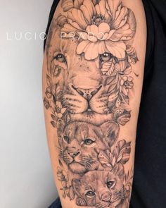 a woman's arm with tattoos on it and two lions in the middle, surrounded by flowers