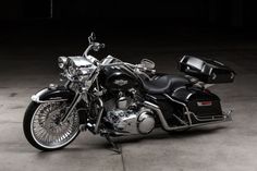 a black and silver motorcycle parked in a parking lot next to a wall with lights on it