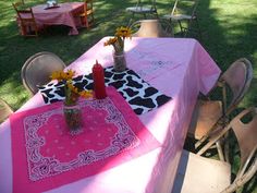 a pink table cloth with black and white designs on it is set up for a party