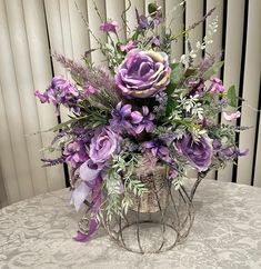 a basket filled with purple flowers sitting on top of a white tablecloth covered table