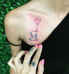 a woman with a tattoo on her shoulder holding a pink heart shaped balloon in front of her chest