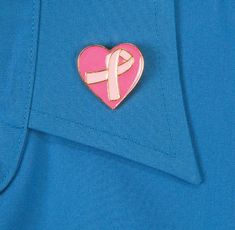 a pink ribbon pin with a heart in the center on a blue shirt lapel