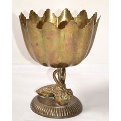 an ornate brass bowl with a bird on the bottom and leaves in the middle, sitting on a pedestal