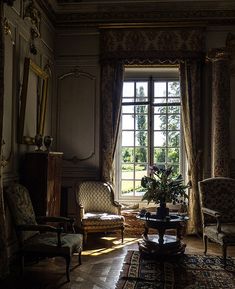 a living room filled with furniture next to a window covered in curtains and drapes