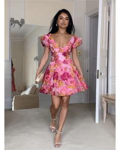 a woman in a pink dress is walking down the hallway with her hand on her hip