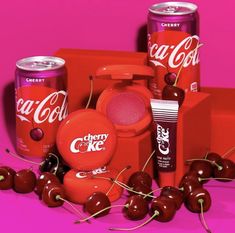 an assortment of coca - cola products and cherries on a pink background