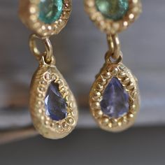 "18k solid dangle and drop gold earrings with green Emerald and light purple Amethyst gemstones. Each of these dainty earrings has three parts: The part on the top is an 18k gold small square with a scratch finish. The second part is 18k gold with Round 3 m\"m light Green Emerald. The third part is 18k gold with a light purple Amethyst teardrop. The gemstones are setting by antique style setting. The colors combination of the 18k gold and the Emerald and Amethyst and the slightly different betwe Teardrop Tanzanite Jewelry In Yellow Gold, Gold Tanzanite Teardrop Jewelry, Yellow Gold Tanzanite Jewelry With Matching Earrings, Purple Amethyst Earrings, Solid Gold Earrings, Gold Gift, Gold Earring, Antique Earrings, Amethyst Earrings