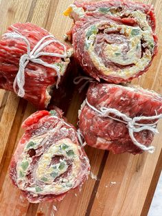 four raw meats wrapped in rope on a wooden cutting board, ready to be cooked