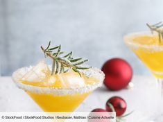 two glasses filled with alcoholic drinks and garnished with rosemary