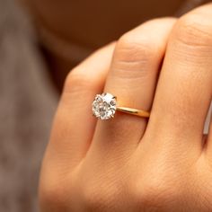 a close up of a person's hand with a diamond ring on their finger