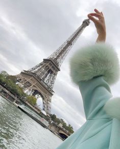 the eiffel tower in paris, france is shown from across the water with someone's hand reaching up