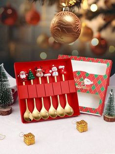 a red box filled with gold spoons next to christmas decorations