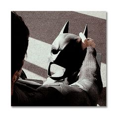 a person wearing a batman mask and pointing at the ground with their hand in front of them